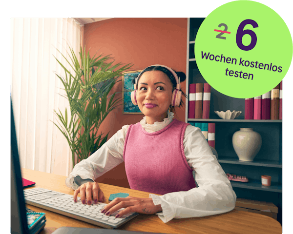 Eine junge Frau mit Kopfhörern, die an einem Schreibtisch arbeitet