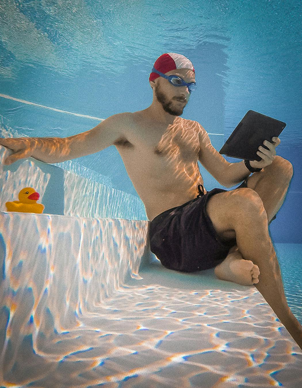 Person, die unter Wasser schwimmt und dabei ein Buch hält.