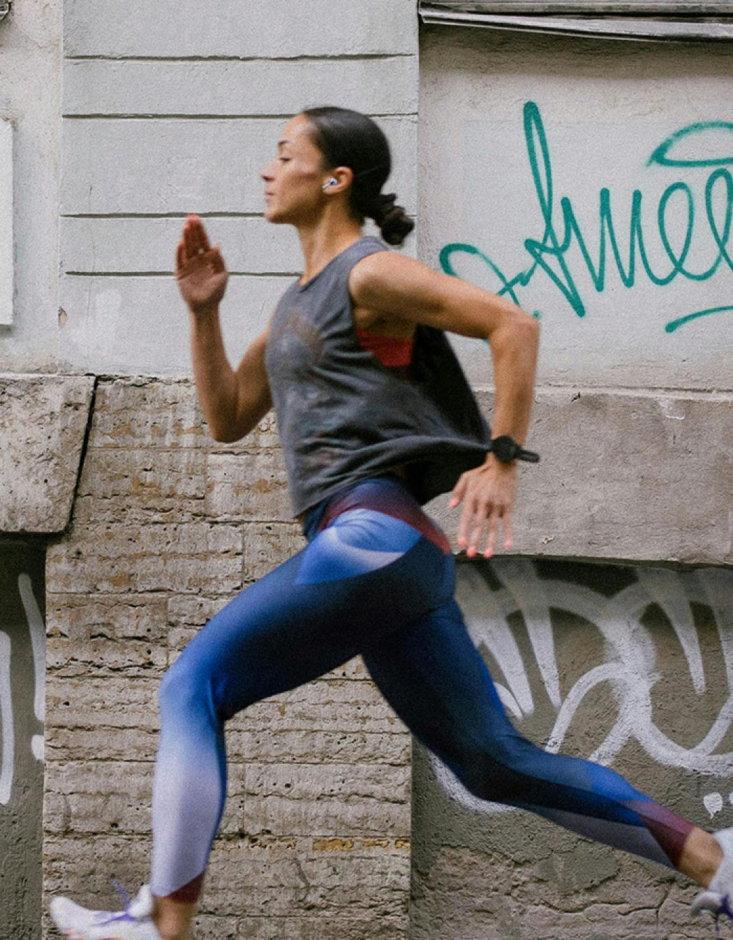 Frau streckt sich beim Training an einer Wand aus.